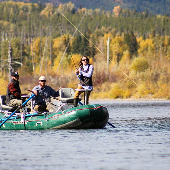 People in a green boat fish on still water.