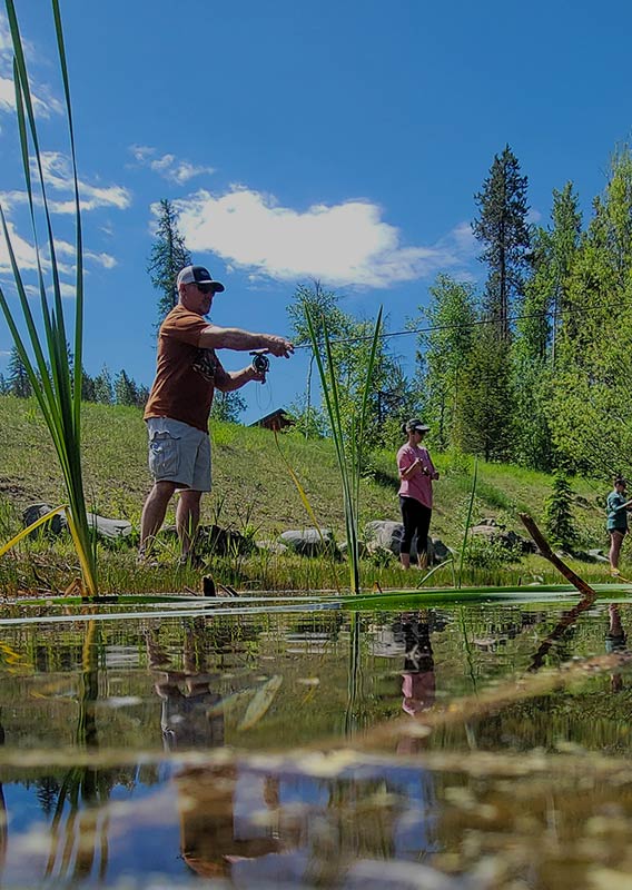 A shot from the water of a man and child practice fishing