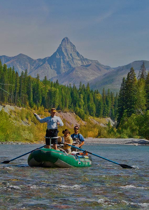 People fish from the riverboat, with a mountain in the background.