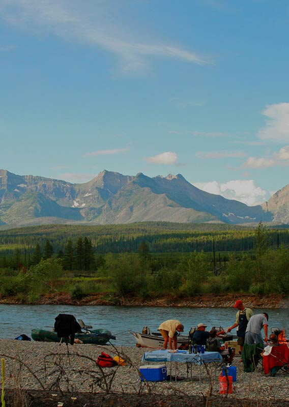 A group sets up camp at the edge of the Flathead River