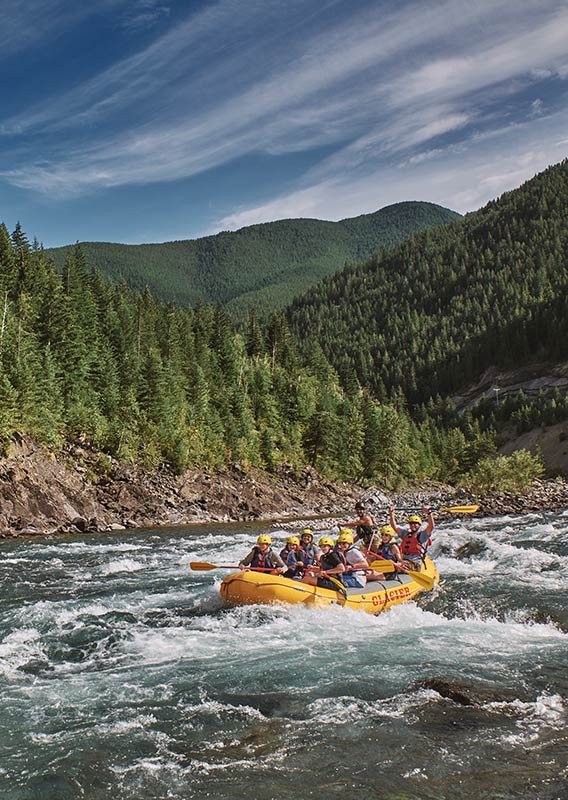 A group of rafters on the water, cheering with their paddles