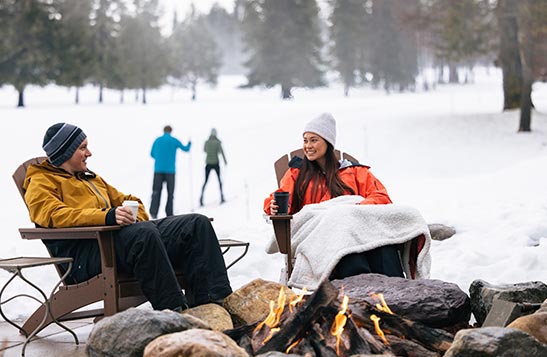 A lodge with large windows covered with snow and lights.