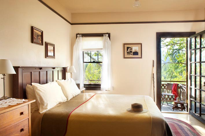 A bed in a hotel room with an open door leading to a balcony