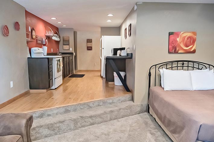 A view from a bedroom and lounge towards a kitchen.