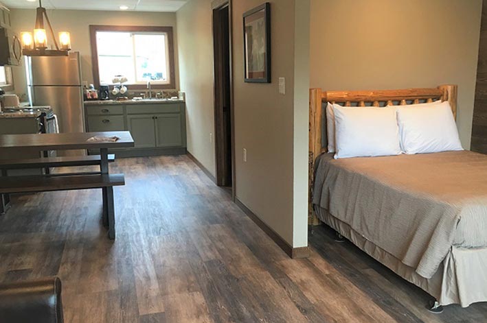 A view from a bedroom and lounge towards a kitchen.