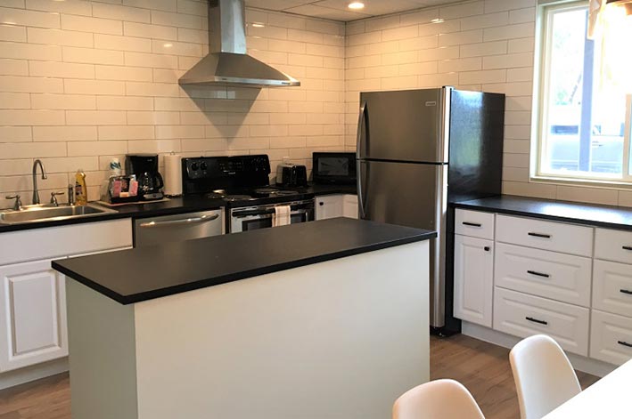 A kitchen with large counter space and chairs at a table.