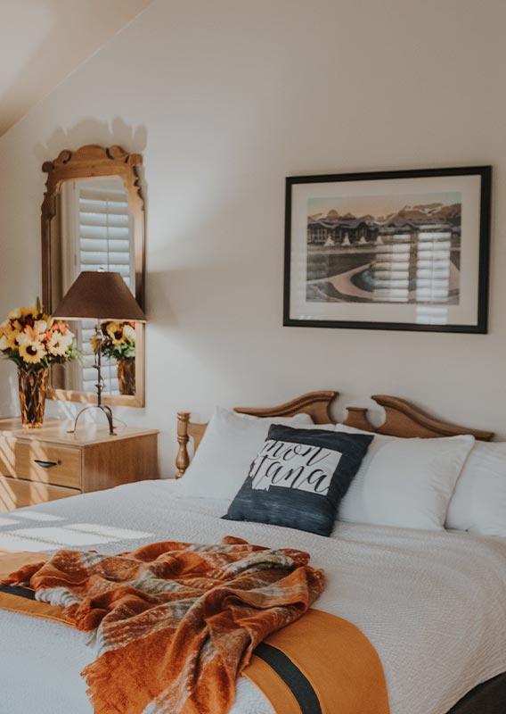 A hotel bed with sunlight shining through a window.