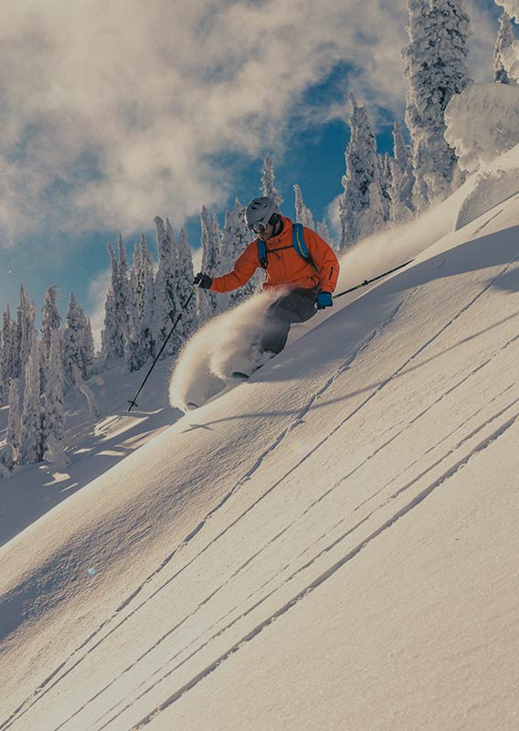 Two skiers speed down a steep slope of fresh snow.
