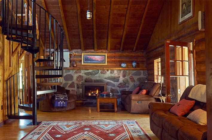 Spacious living room with fireplace and spiral staircase in the Homestead House at St. Mary Village