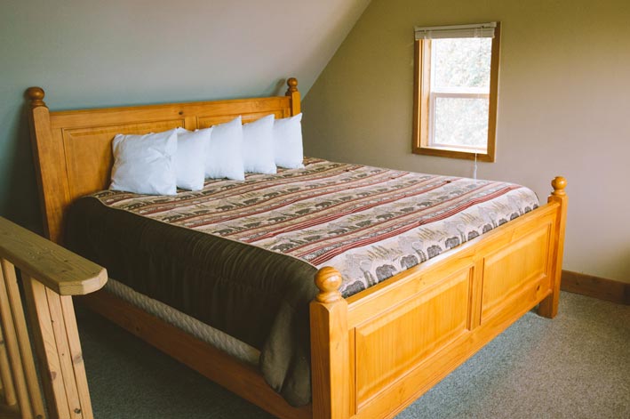 A bed in a loft area of a cabin.