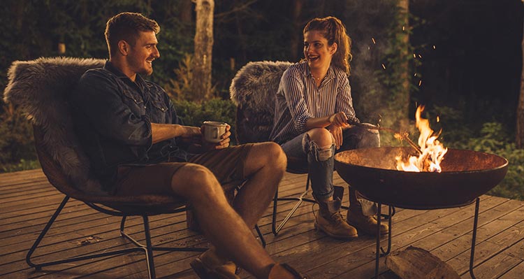 Two people sit around a campfire.