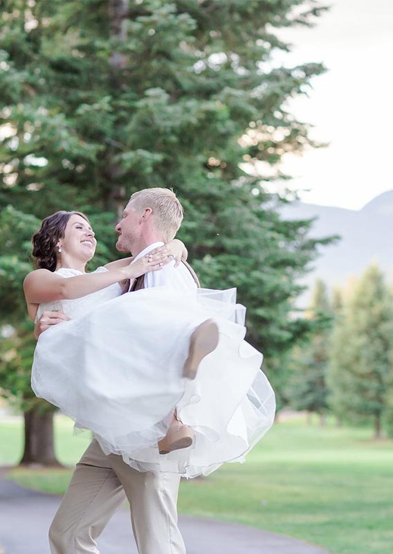 Groom carrying his bride, surrounded by trees