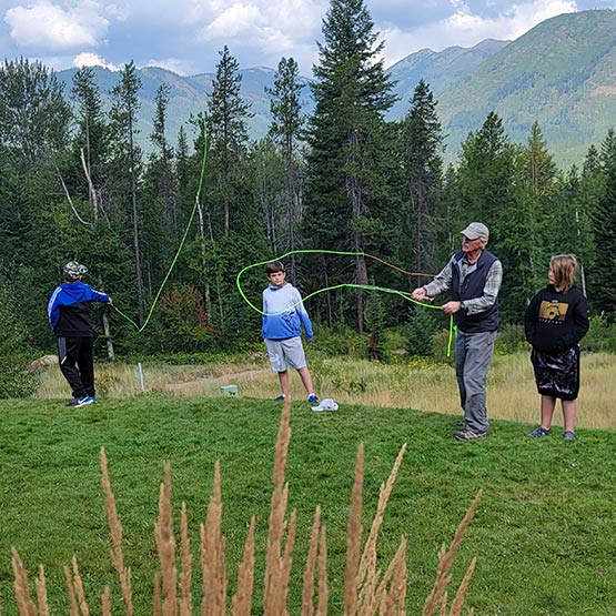 A fishing instructor high fives a a student holding a fish in a net.