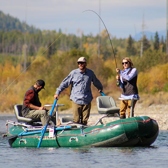 A group of fishers on a green boat in a river.