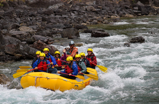 A rafting group paddling through rapids along the Flathead River.