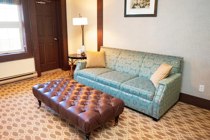 A hotel suite with a sofa and ottoman