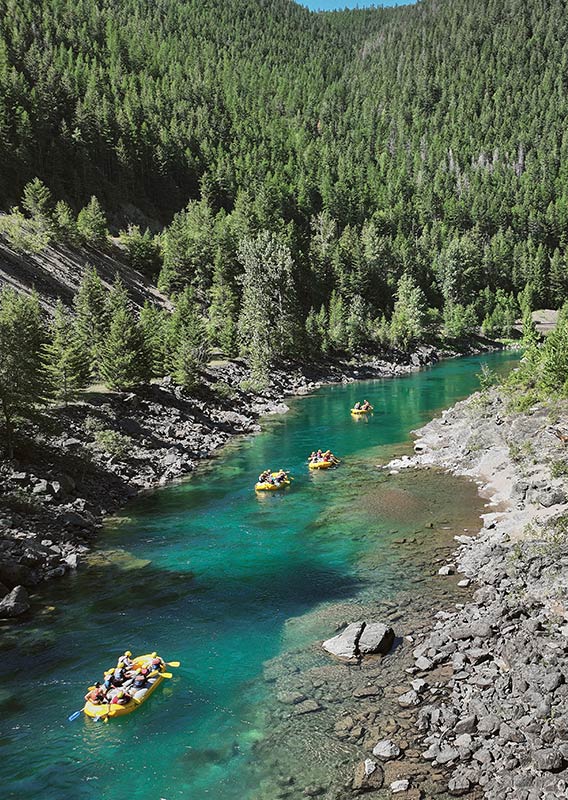 Yellow rafts float down a calm turquoise river.