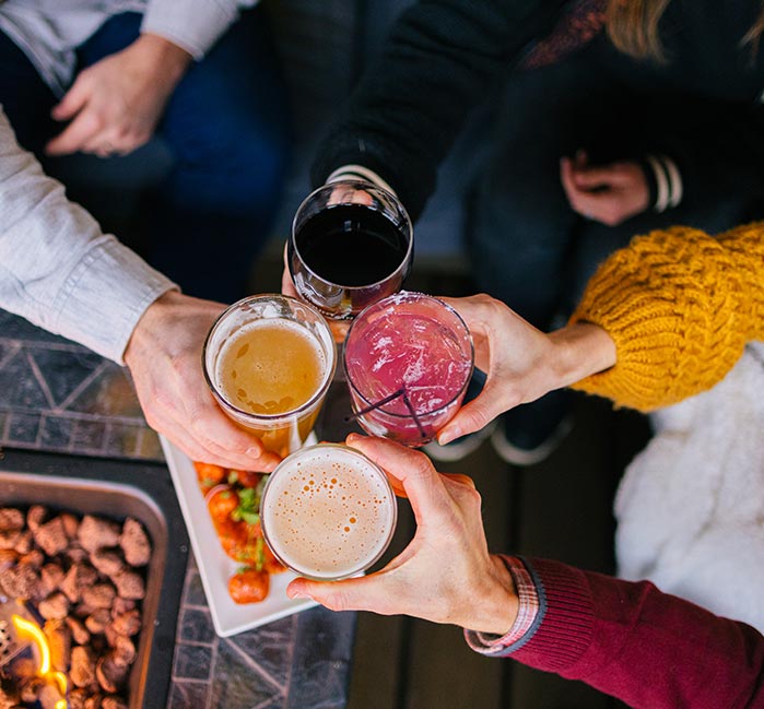 Four hands cheer cocktails from above.