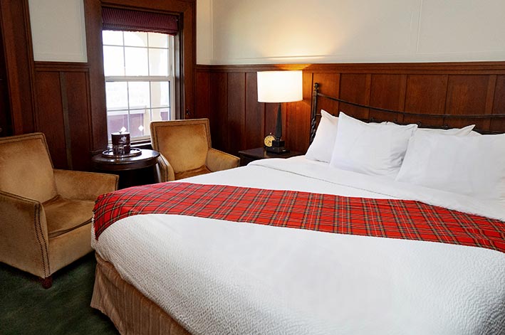 Well-appointed hotel room with one king bed, sitting area and views of Waterton Lake