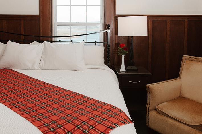 A hotel bed and chair next to a window.