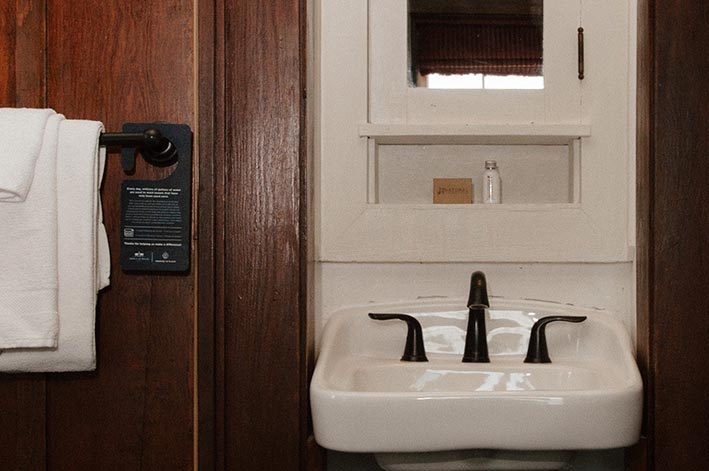 A hotel room sink in a wood paneled room.