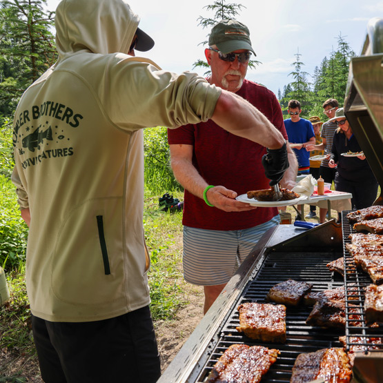 A rafting guide serving barbecue ribs to a guest.