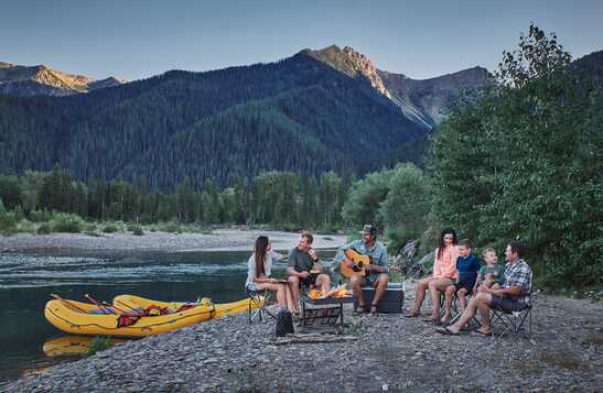 Family sitting by a lake with a mountain view