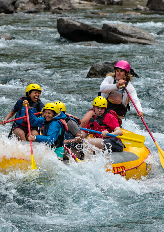 A rafting group paddling through rough rapids