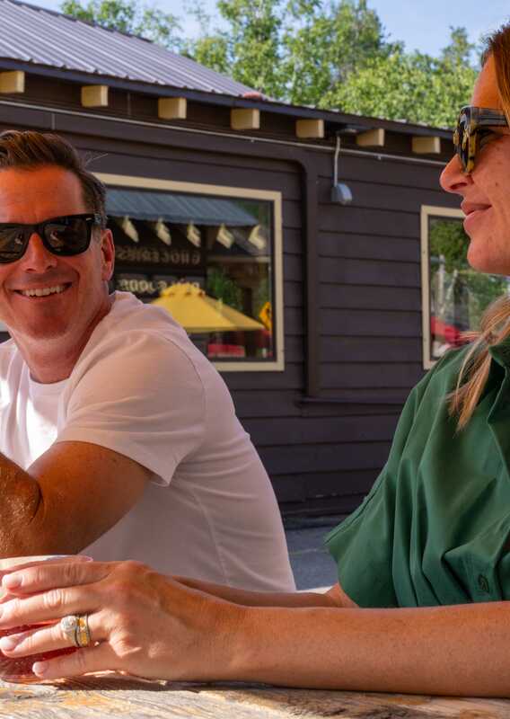 Two people sitting at a picnic table outside Freda's Bar.