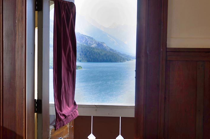 An open door and balcony overlooking a lake.
