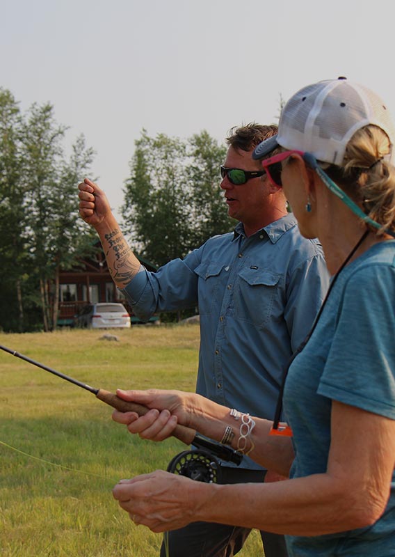 A fishing instructor teaches a client how to cast a fly rod.