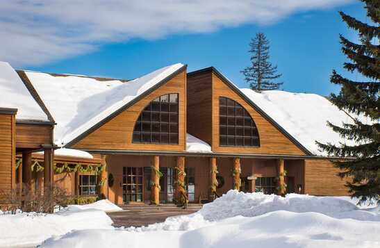 The exterior of a hotel in winter, with snow on the roof and out front.